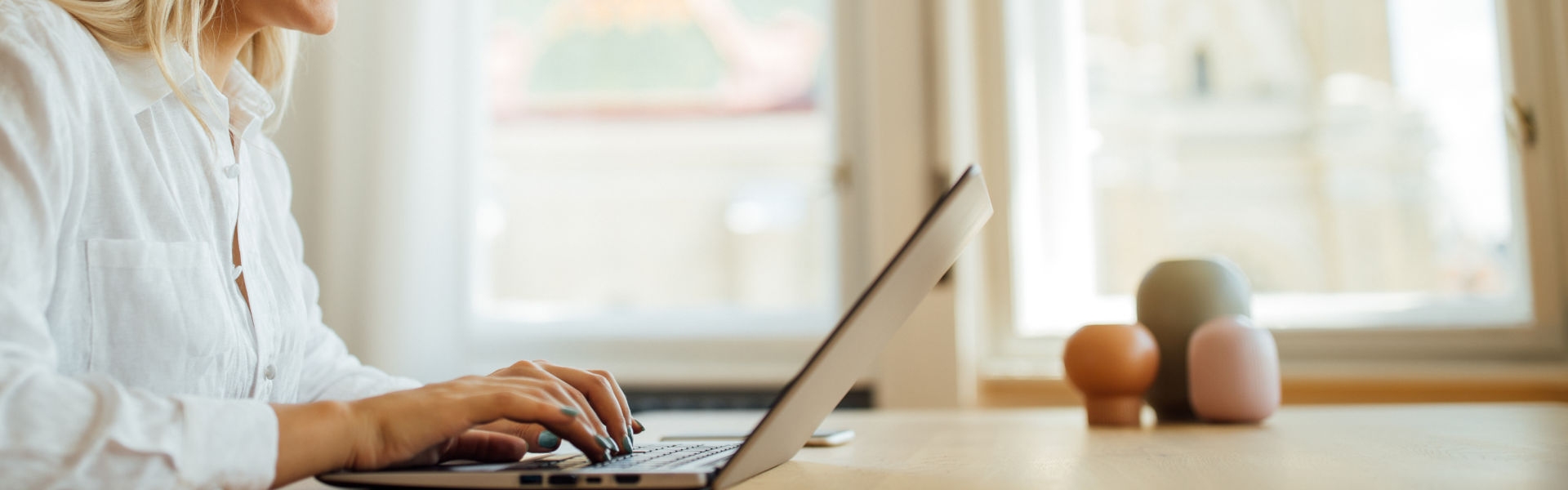 Side view portrait of a cheerful young woman using laptop at home office.